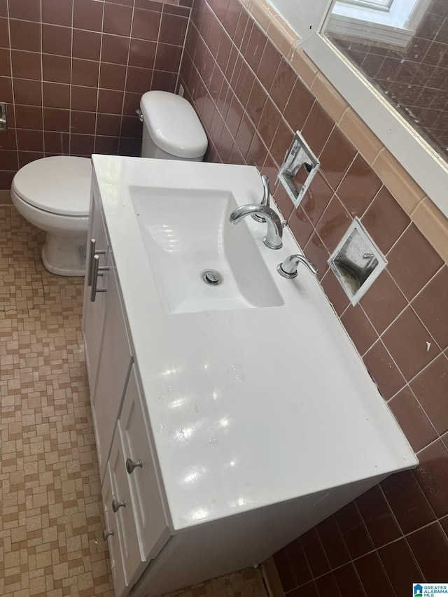 bathroom with vanity, toilet, tile patterned flooring, and tile walls