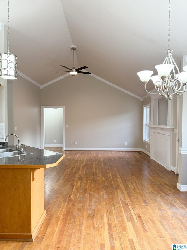 interior space featuring ceiling fan with notable chandelier, sink, ornamental molding, and vaulted ceiling