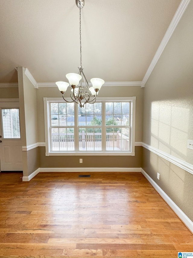 unfurnished dining area with plenty of natural light, ornamental molding, a chandelier, and light hardwood / wood-style flooring