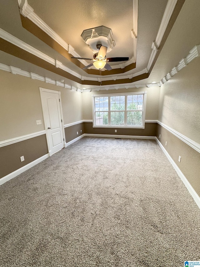 spare room featuring ceiling fan, carpet, ornamental molding, and a raised ceiling