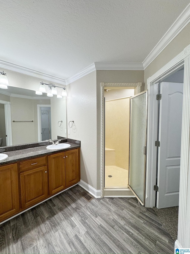 bathroom featuring vanity, a shower with door, ornamental molding, and hardwood / wood-style floors