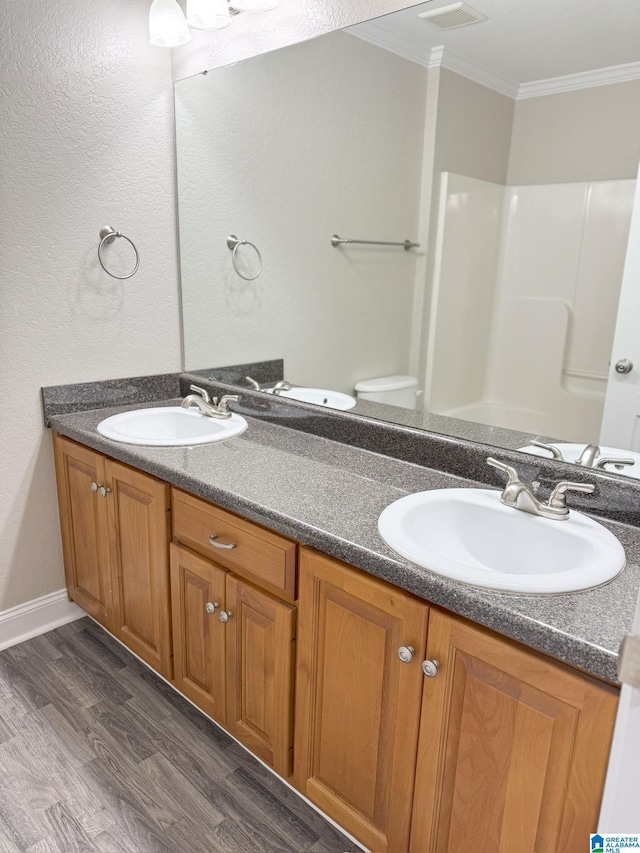 bathroom with toilet, hardwood / wood-style floors, walk in shower, ornamental molding, and vanity