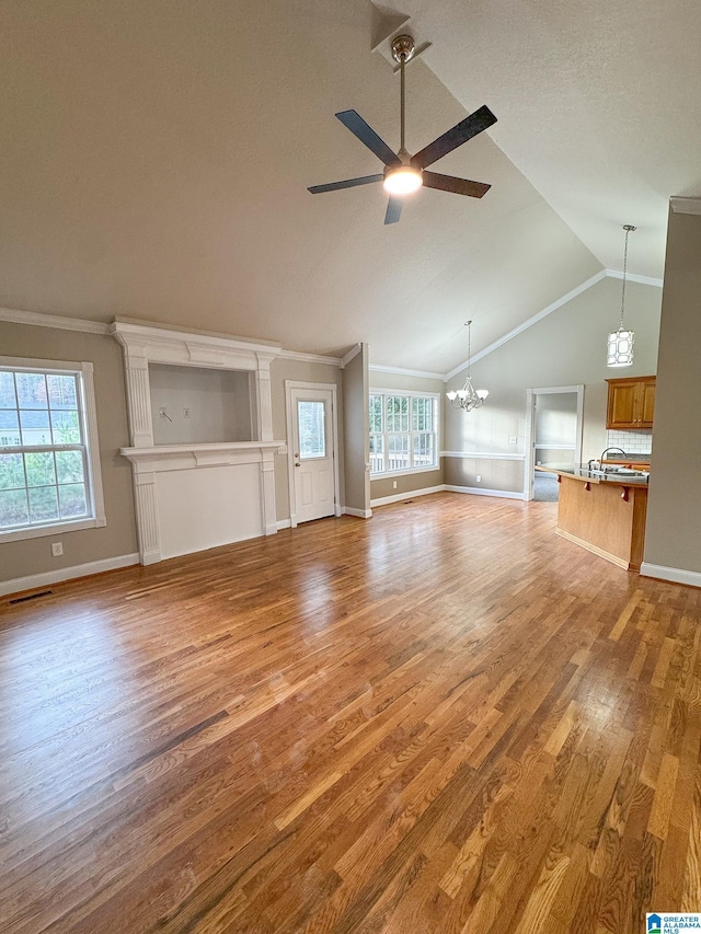 unfurnished living room with crown molding, vaulted ceiling, ceiling fan with notable chandelier, and light hardwood / wood-style floors