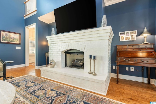 interior space featuring a brick fireplace, light hardwood / wood-style flooring, and ornamental molding