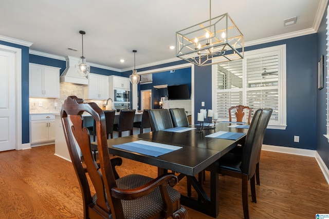 dining space with wood-type flooring, a notable chandelier, and crown molding