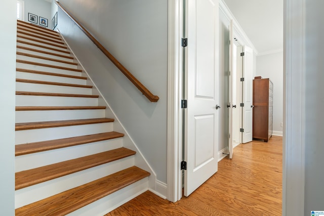 stairway featuring wood-type flooring and crown molding