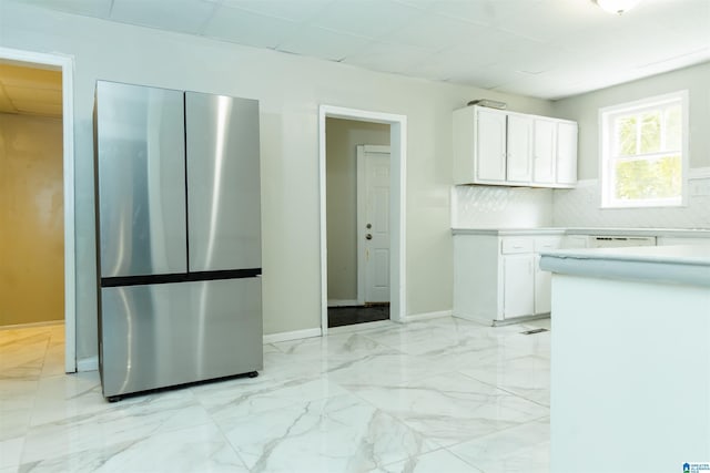 kitchen featuring decorative backsplash, white cabinets, and stainless steel refrigerator