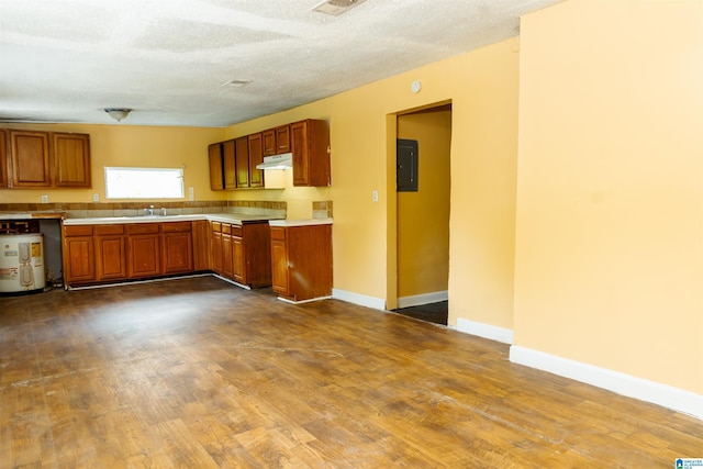 kitchen featuring a textured ceiling, water heater, wood-type flooring, sink, and electric panel