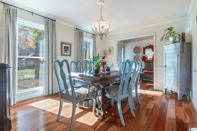 dining room with hardwood / wood-style flooring, a textured ceiling, crown molding, and a notable chandelier