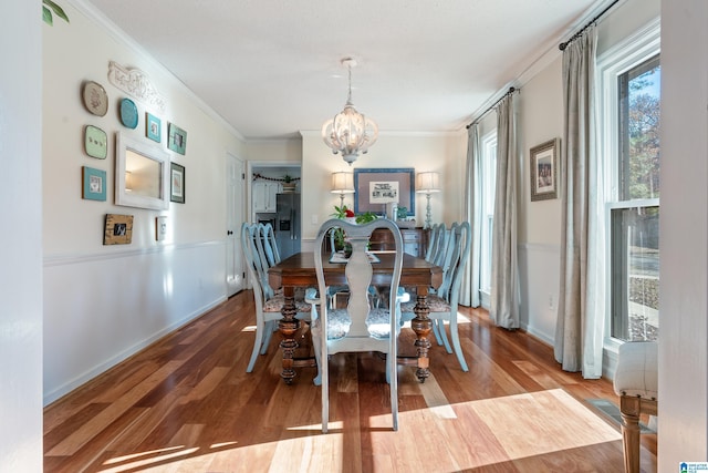 dining space featuring an inviting chandelier, ornamental molding, and hardwood / wood-style floors