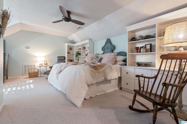 bedroom with ceiling fan, a textured ceiling, light carpet, and lofted ceiling