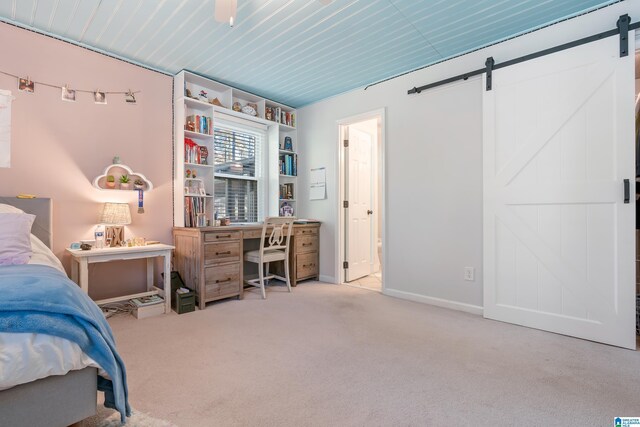 bedroom with a barn door and light colored carpet