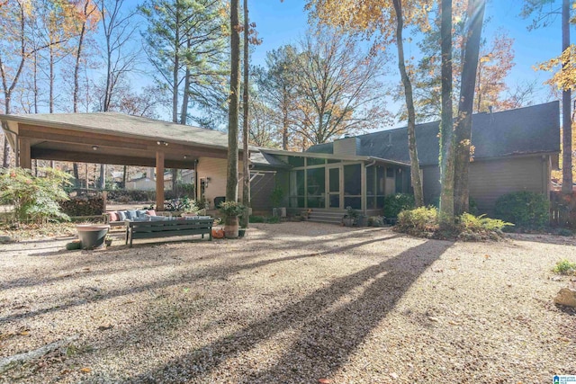 rear view of house featuring a sunroom and a carport