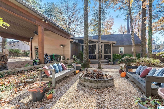 view of patio featuring ceiling fan, a sunroom, and an outdoor living space with a fire pit