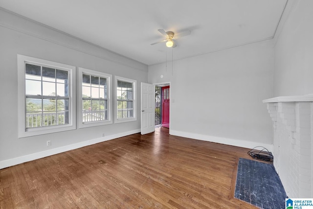 empty room with ceiling fan, ornamental molding, a fireplace, and hardwood / wood-style flooring