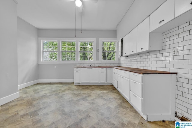 kitchen featuring white cabinetry, wooden counters, ceiling fan, backsplash, and ornamental molding