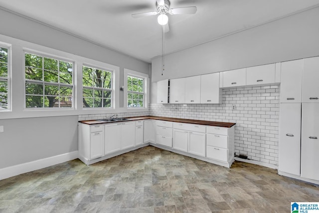 kitchen featuring ceiling fan, tasteful backsplash, sink, white cabinets, and wood counters