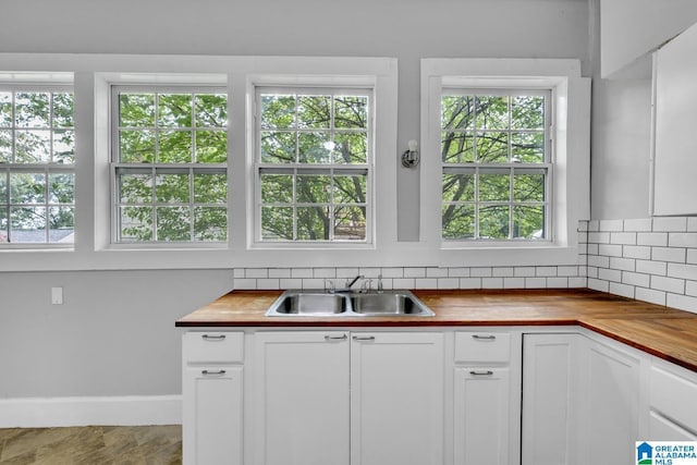 kitchen with white cabinets, sink, and wood counters