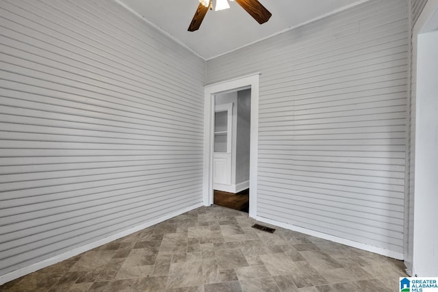 unfurnished room with ceiling fan, ornamental molding, and wood walls