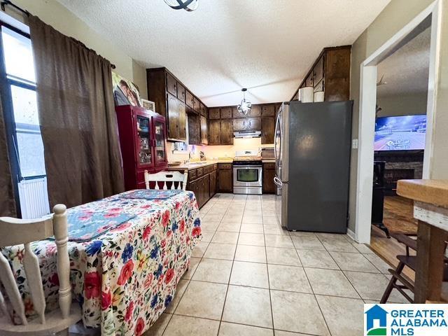 kitchen featuring a textured ceiling, appliances with stainless steel finishes, dark brown cabinetry, sink, and light tile patterned floors