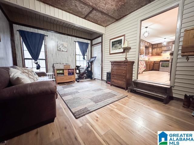 living room with light hardwood / wood-style flooring and wooden walls