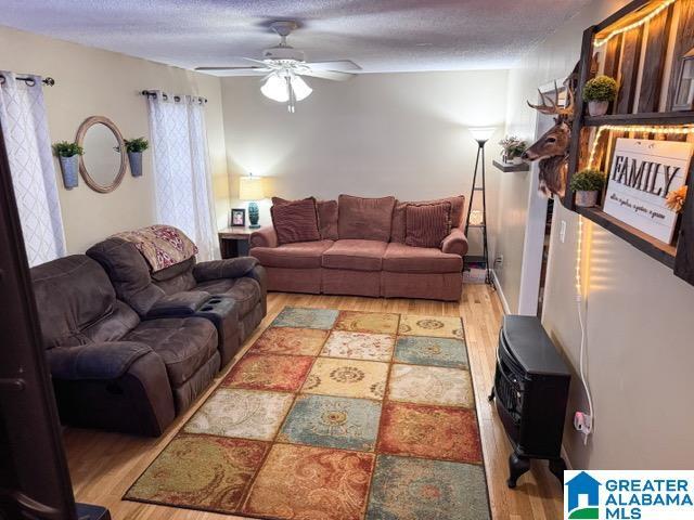 living room with a textured ceiling, light hardwood / wood-style flooring, and ceiling fan