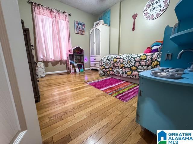 bedroom featuring multiple windows, hardwood / wood-style floors, and a textured ceiling