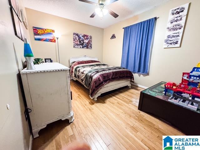 bedroom with light hardwood / wood-style floors, a textured ceiling, and ceiling fan