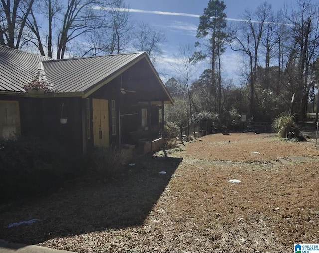 view of property exterior with a standing seam roof, ceiling fan, and metal roof