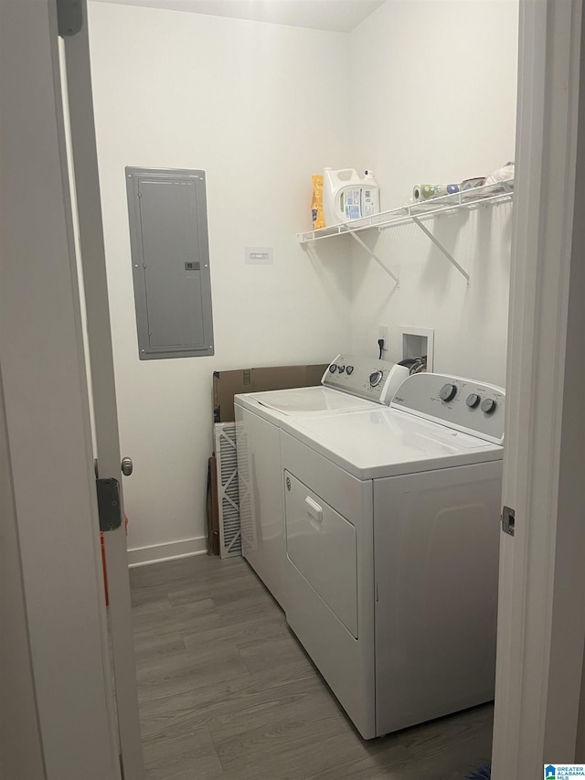 laundry area with light wood-type flooring, washer and dryer, and electric panel