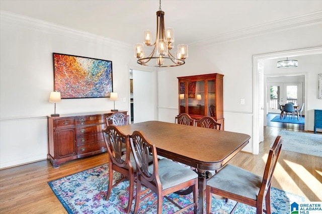 dining area featuring ornamental molding, a chandelier, light wood-type flooring, and french doors