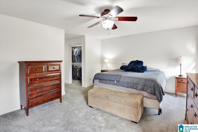 carpeted bedroom featuring a walk in closet, ceiling fan, and a closet