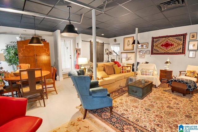 living room featuring a paneled ceiling and a barn door