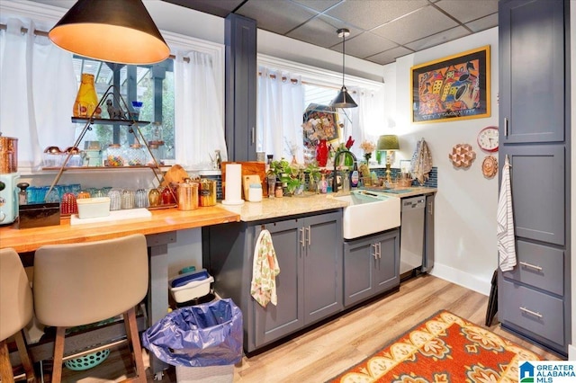 kitchen featuring a paneled ceiling, pendant lighting, dishwasher, gray cabinetry, and light wood-type flooring