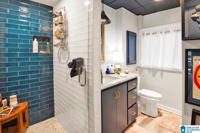 bathroom with vanity, tiled shower, and toilet