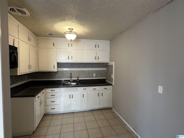 kitchen with light tile patterned floors, white cabinetry, tasteful backsplash, and sink