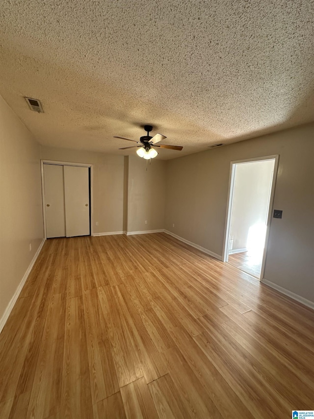 unfurnished bedroom featuring light wood-type flooring, ceiling fan, a textured ceiling, and a closet