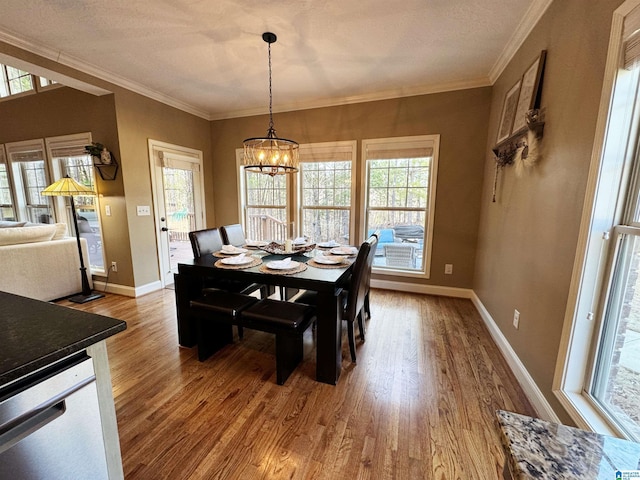 dining space featuring hardwood / wood-style flooring, a textured ceiling, crown molding, and a chandelier