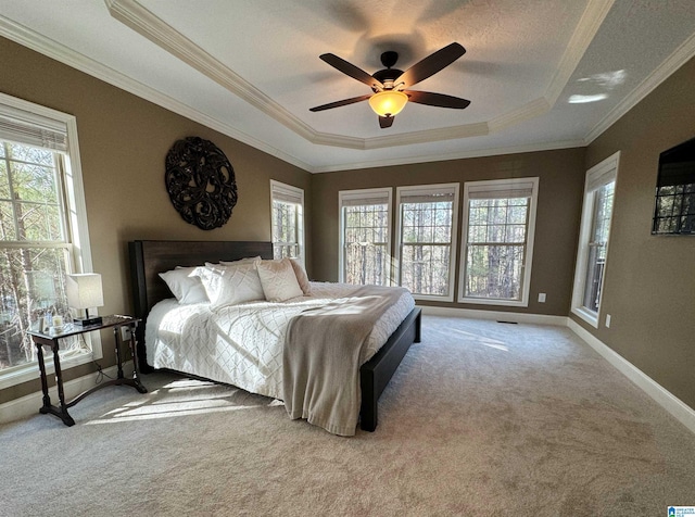 carpeted bedroom featuring ceiling fan, ornamental molding, and a raised ceiling