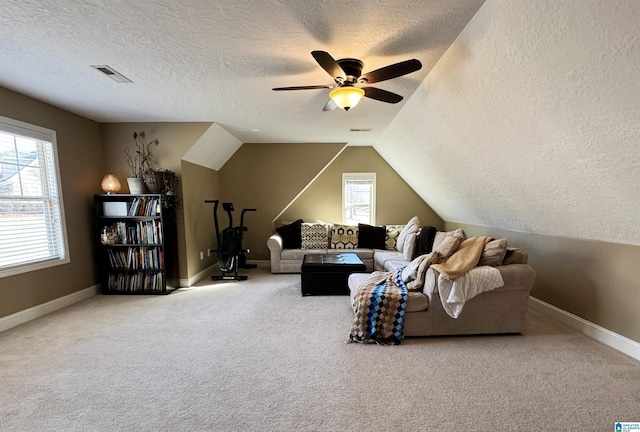 carpeted living room with ceiling fan, vaulted ceiling, plenty of natural light, and a textured ceiling