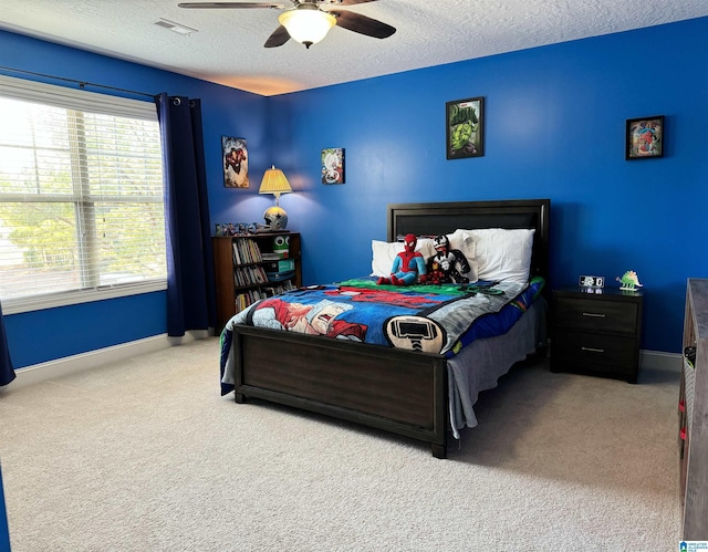 carpeted bedroom featuring ceiling fan and a textured ceiling