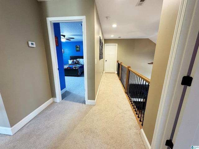 corridor featuring vaulted ceiling and light colored carpet