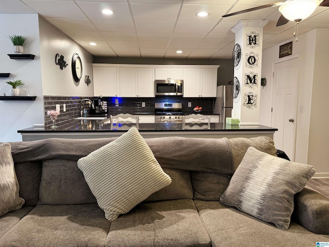 living room featuring a paneled ceiling, ceiling fan, and sink