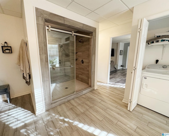 bathroom featuring a paneled ceiling, a shower with shower door, and washer / clothes dryer