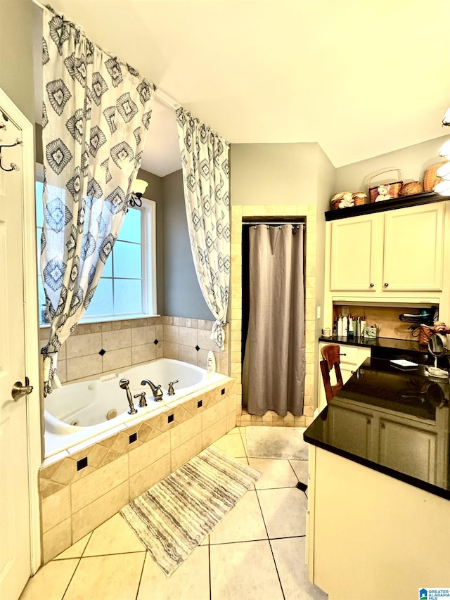 bathroom featuring tiled bath, vanity, and tile patterned flooring