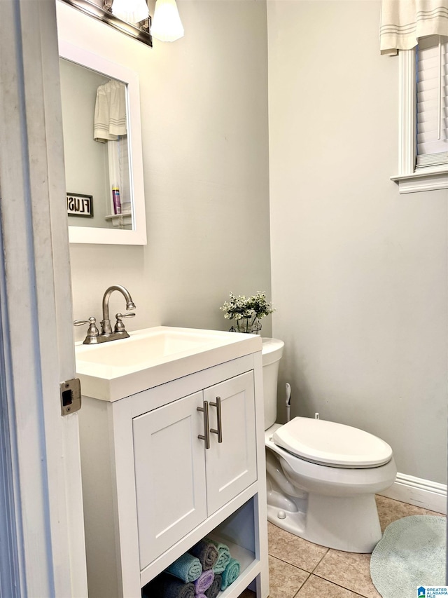 bathroom with toilet, vanity, and tile patterned flooring