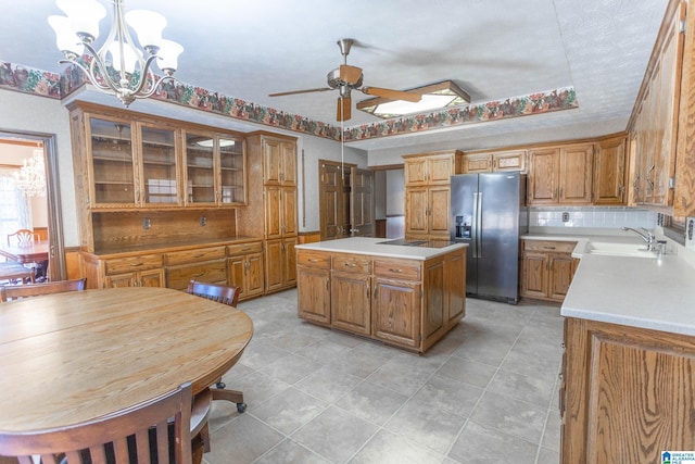 kitchen featuring ceiling fan with notable chandelier, a center island, decorative light fixtures, sink, and stainless steel fridge