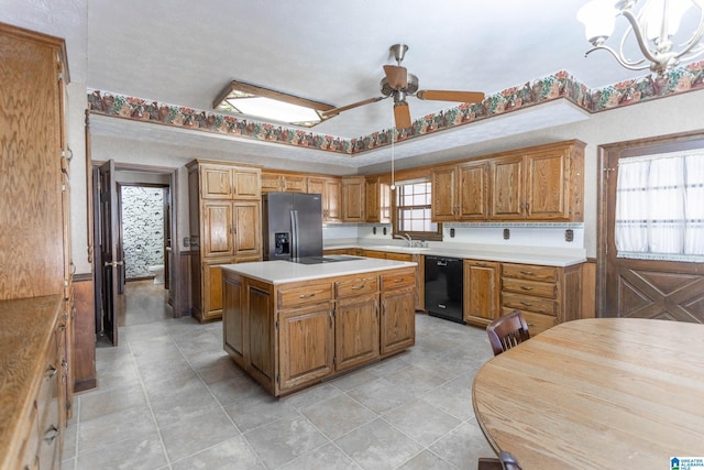 kitchen featuring ceiling fan with notable chandelier, pendant lighting, black appliances, a kitchen island, and a raised ceiling