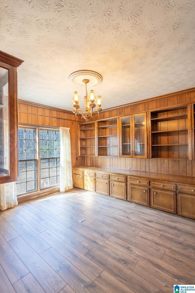 interior space featuring hardwood / wood-style flooring, a textured ceiling, built in features, and a notable chandelier