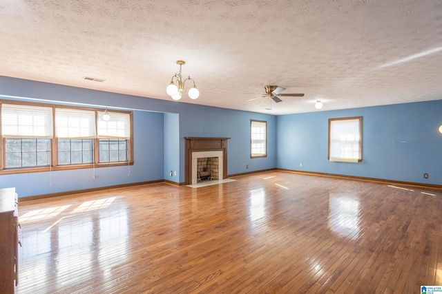 unfurnished living room featuring ceiling fan with notable chandelier, a textured ceiling, and light wood-type flooring